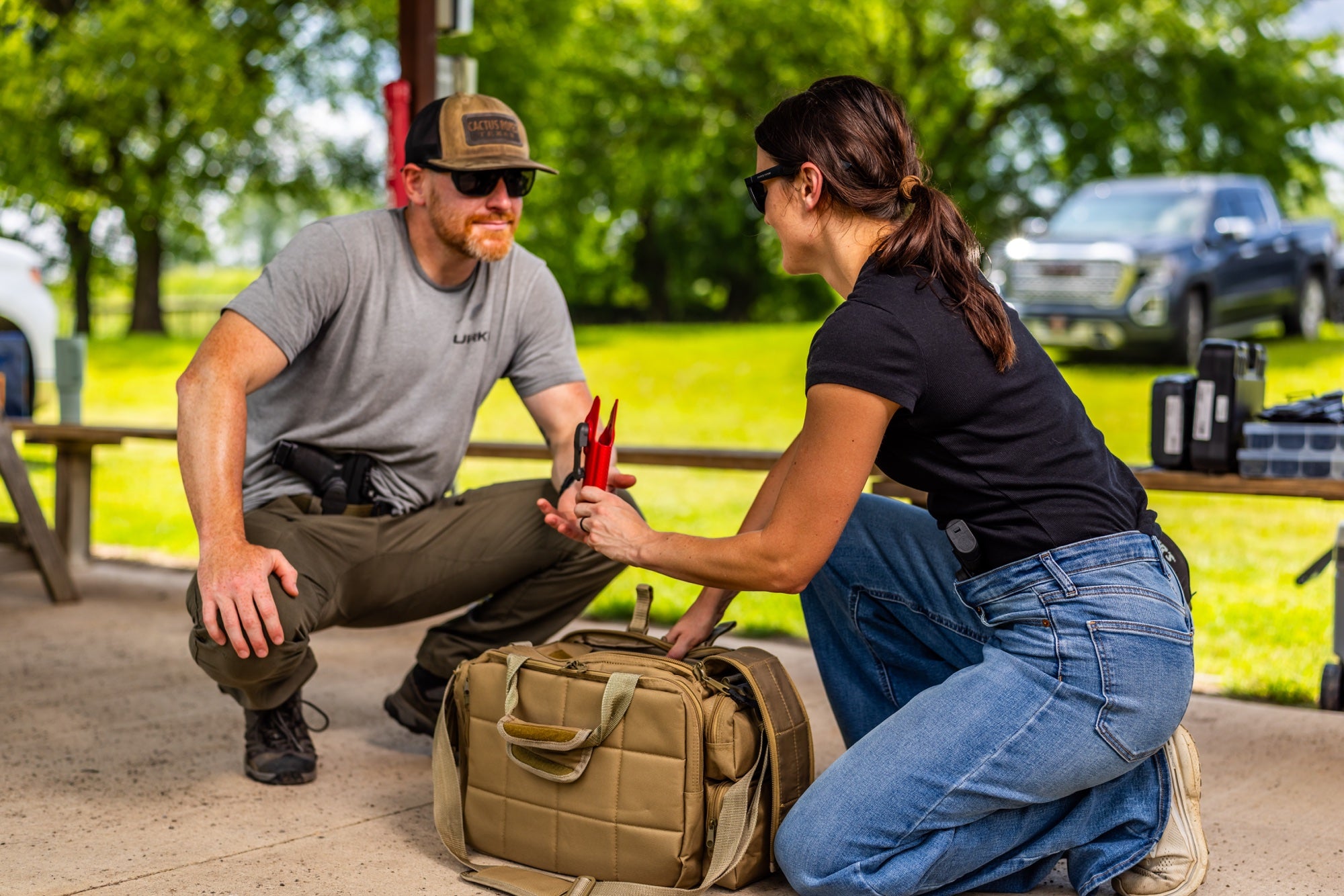 Man and woman wearing Clinger holsters while preparing range gear outdoors